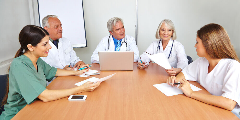 Five registered nurses within a healthcare facility working on a report.