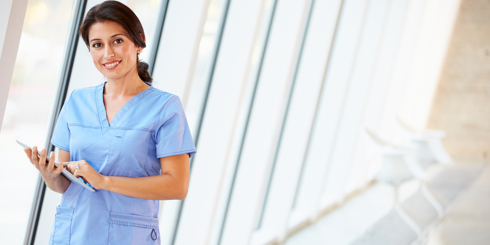 A nursing staff working as an agency nurse stands in a hospital corridor.