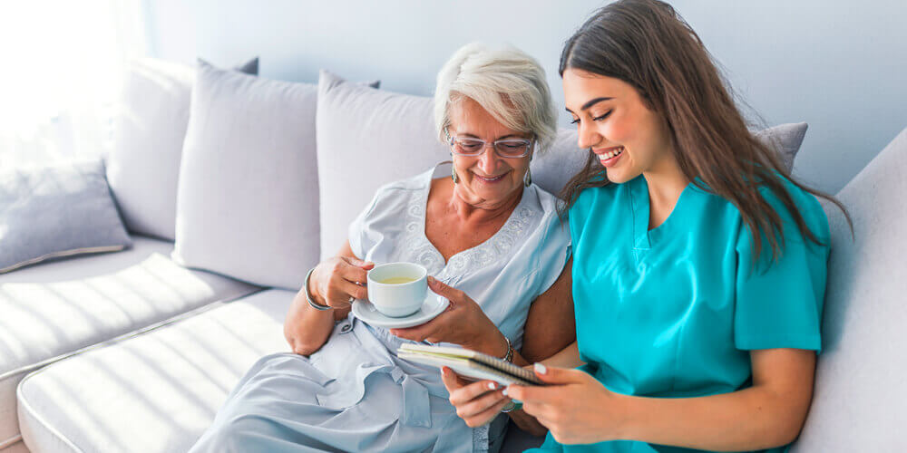 A smiling charge nurse in uniform holding a tab with patient records.