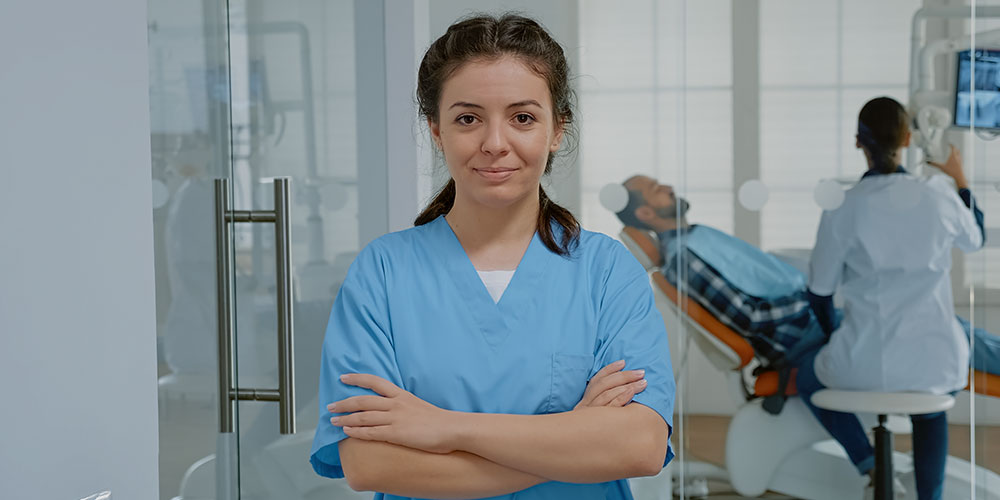 A smiling charge nurse in uniform holding a tab with patient records.