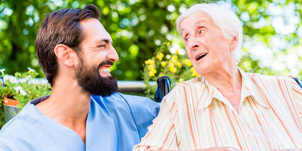 A support worker assists an elderly woman in a wheelchair at her home.