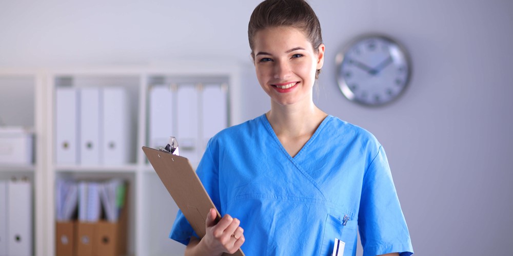 A nurse smiles as she poses for a photograph while holding a client file.