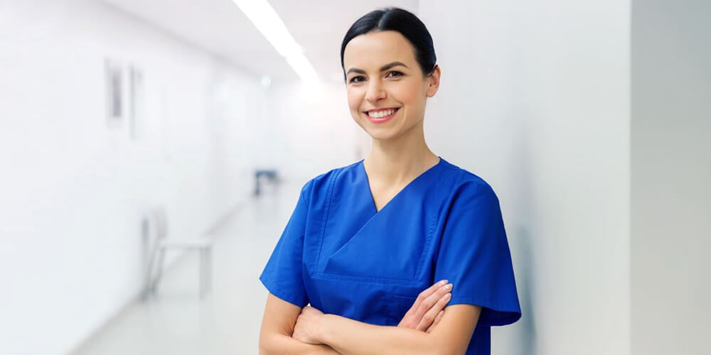 A smiling charge nurse in uniform holding a tab with patient records.