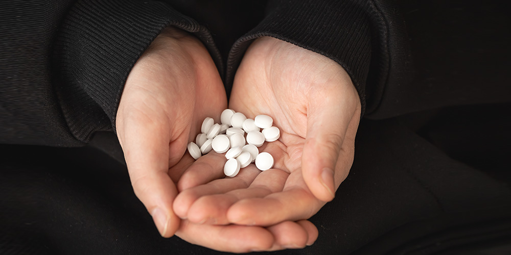 Two nurses converse and take notes about medications in the pharmacy.