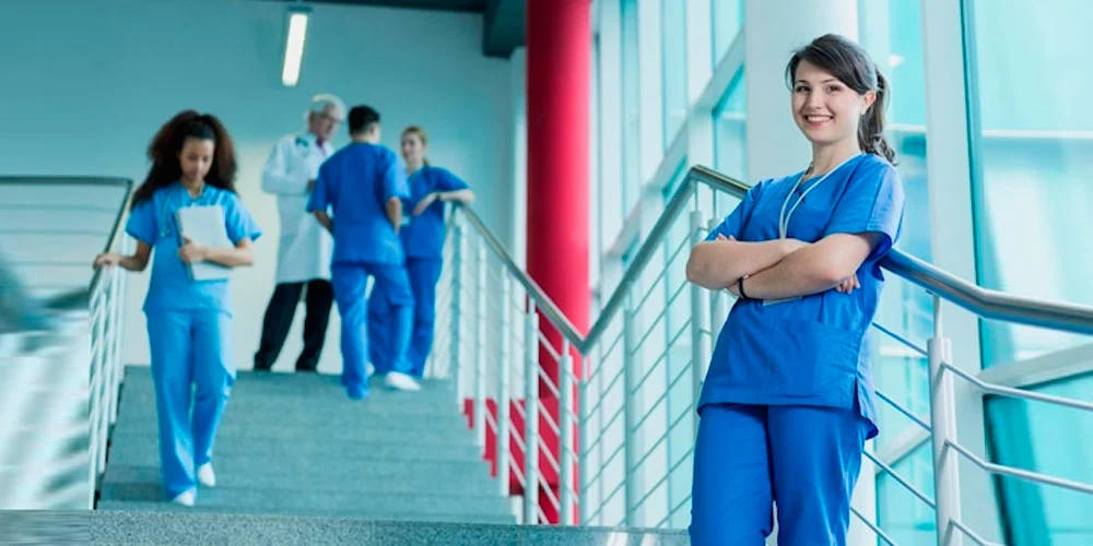 A nursing staff working as an agency nurse stands in a hospital corridor.