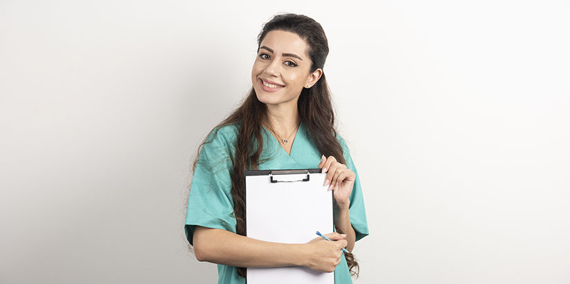 A smiling charge nurse in uniform holding a tab with patient records.