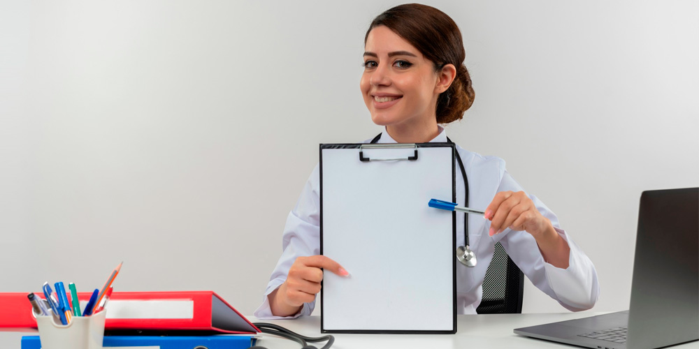 A nurse educator stands at the front of a classroom, in front of a group of nurses.