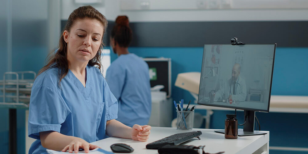 A professional nurse advocate converses with a nurse in an office.