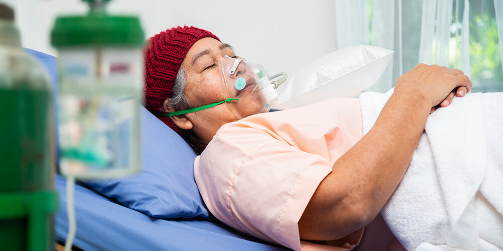 An oncology nurse holding hands of a patient providing compassionate support.