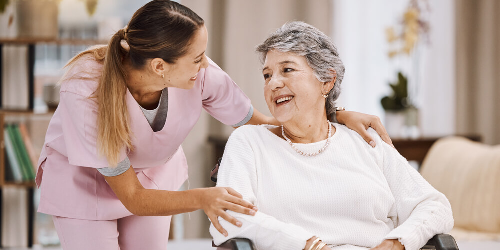 A supportive healthcare assistant providing support to an elderly patient in a wheelchair