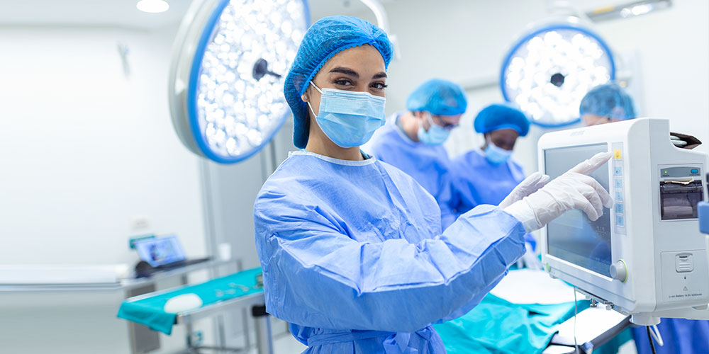 A nurse standing in a ward while a doctor examines the patient.