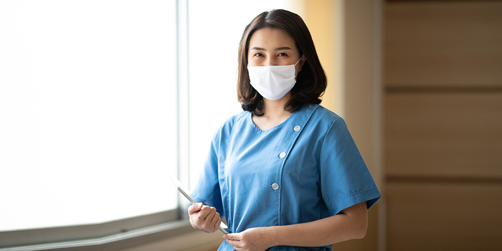 A travel nurse wearing a mask handling patient document