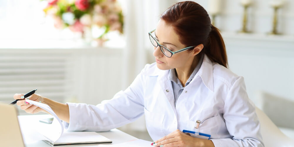 A travel nurse wearing a mask handling patient document