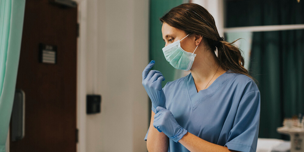 A travel nurse wearing a mask handling patient document